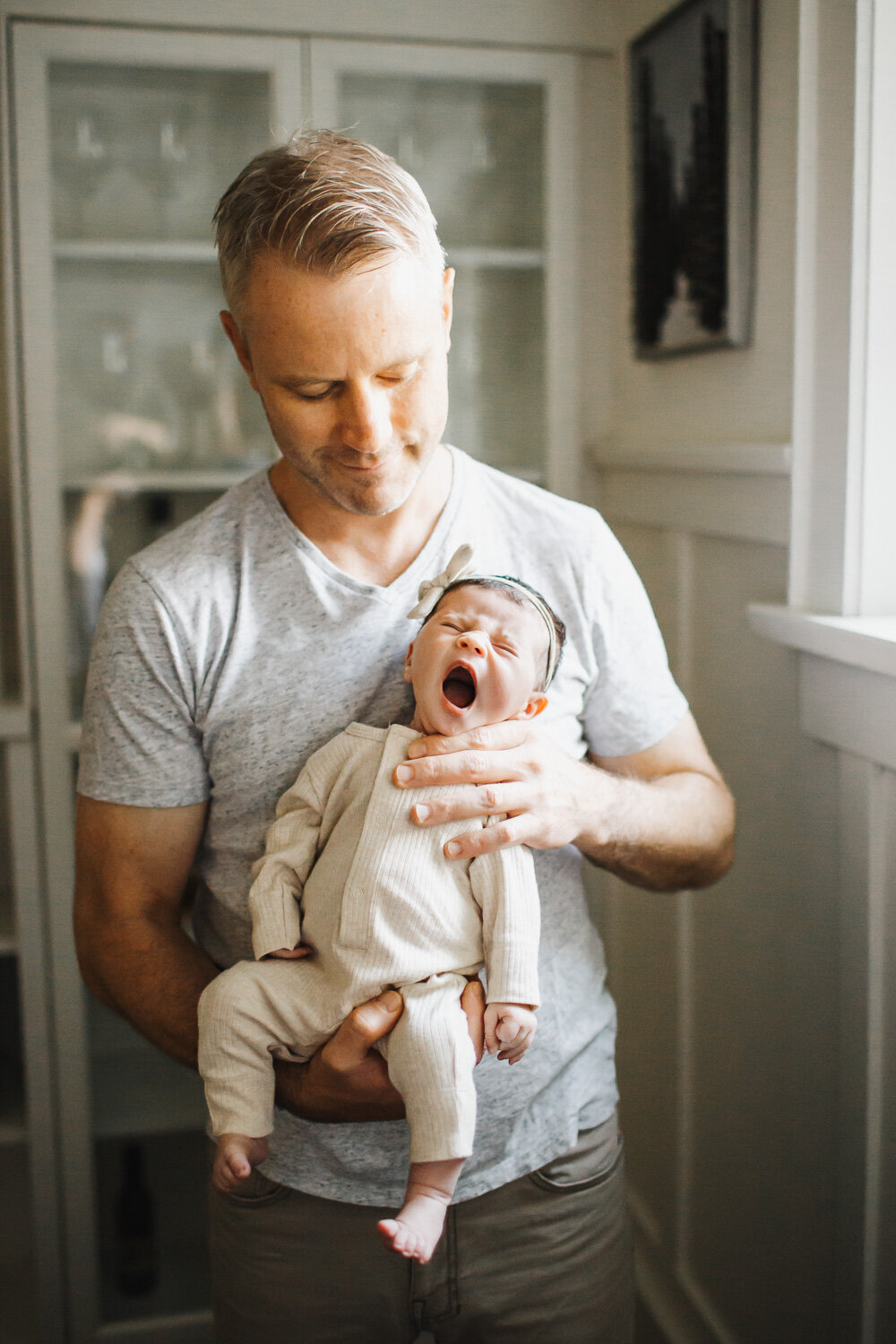 dad holding yawning baby girl during in home toronto newborn photography session