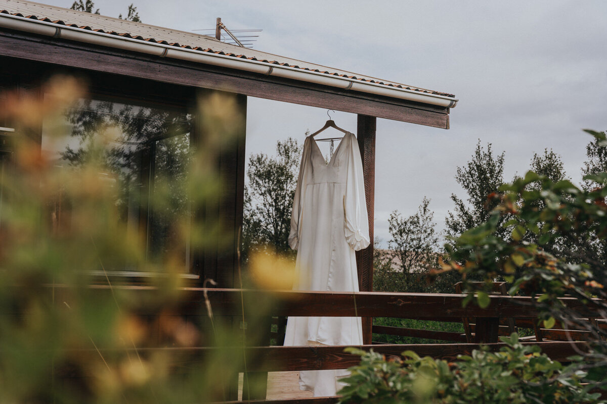 Brides wedding gown hangs on the porch of the Iceland cottage 
