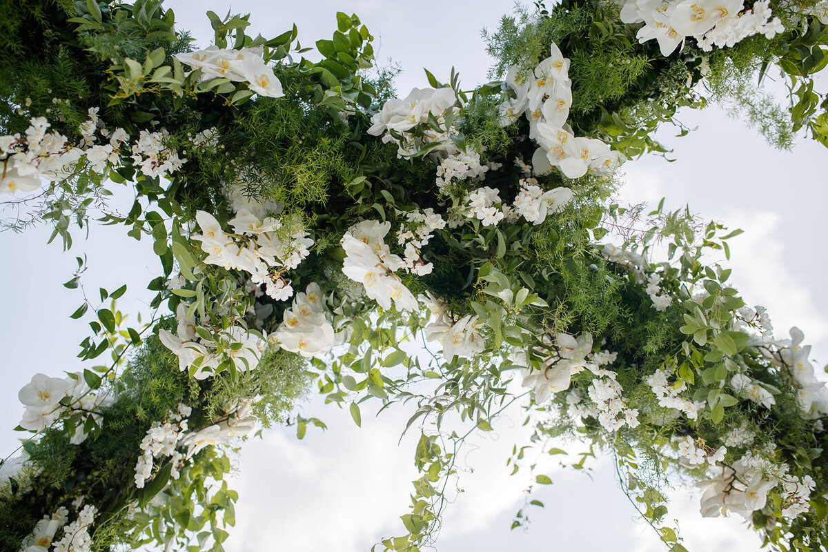 Lush greenery and white florals create a vibrant overhead arch.