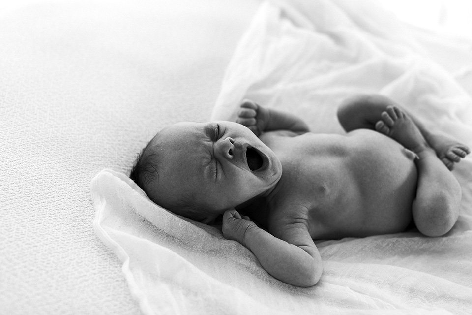Baby yawning on a white blanket