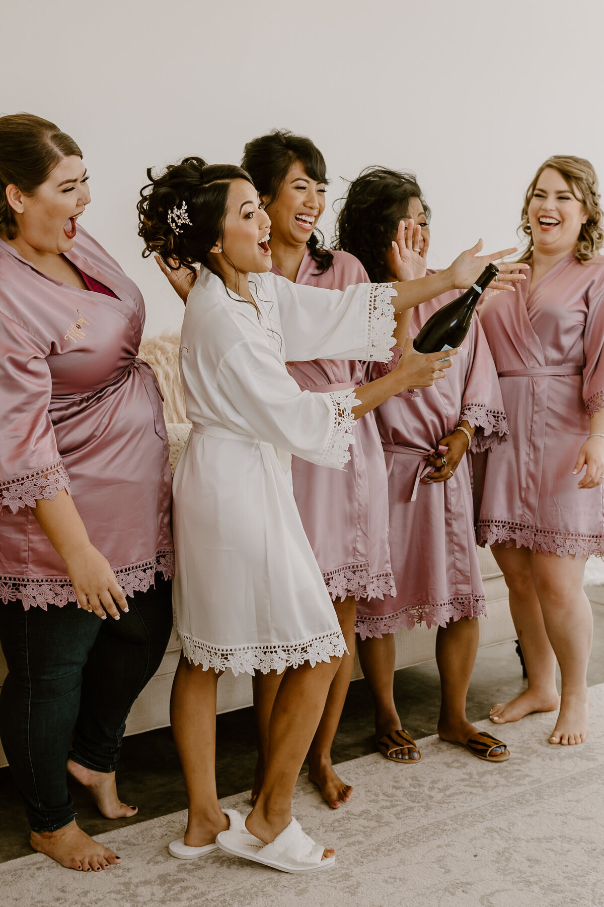wedding-getting-ready-bridesmaids-champagne-pop-laughing-emerald-hills-events-promise-city-iowa-des-moines-wedding-photographer-storyteller-collective-photo-co