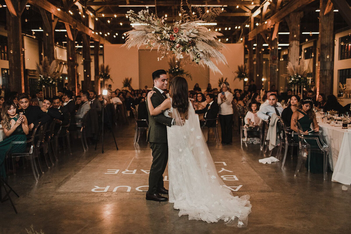 Bride and groom first dance during wedding reception at The Pipe Shop Venue, decorated with pampas grass and stunning pink florals, featured on the Brontë Bride Vendor Guide.