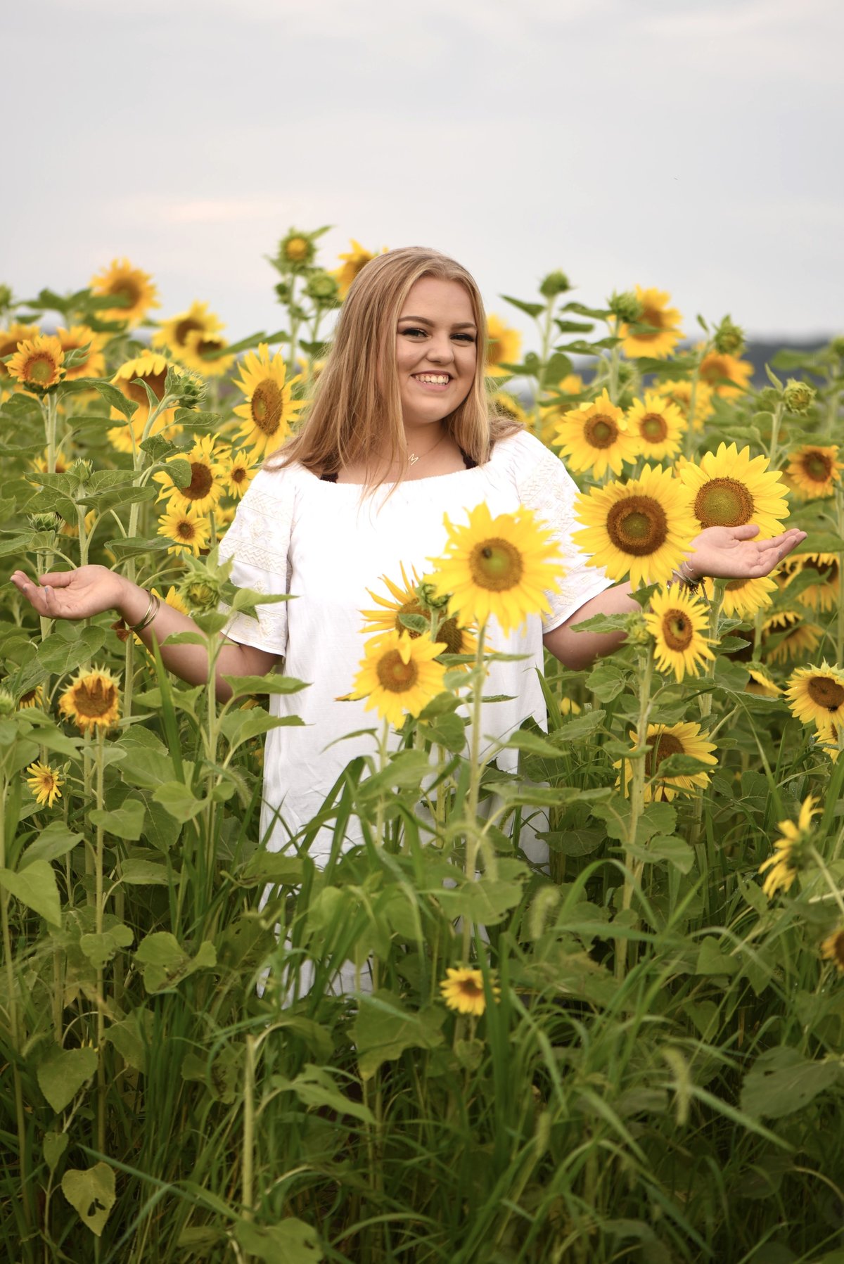 Senior girl in white dress in sunflower field
