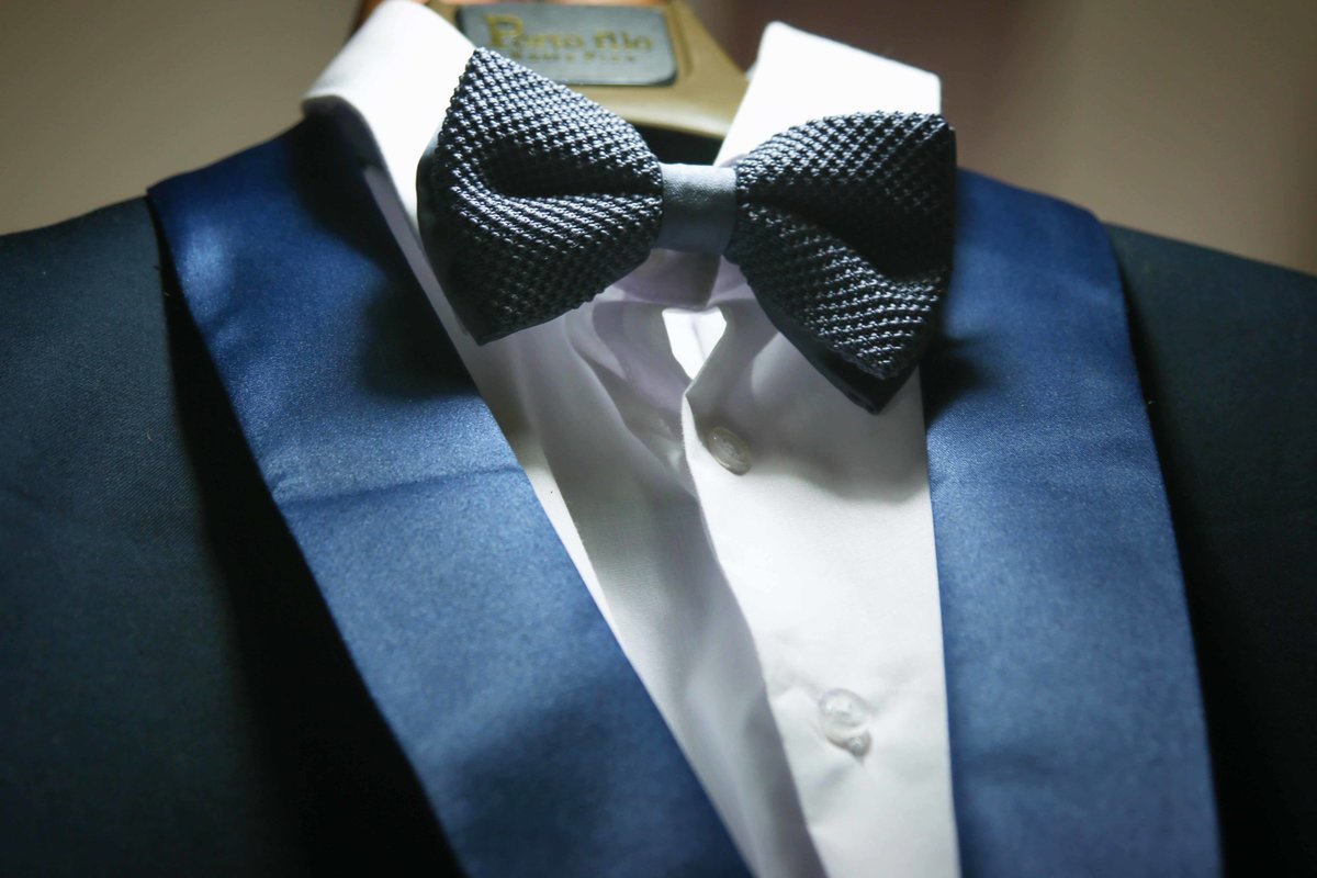 Close up of blue bow tie and tuxedo on a hanger. Photo by Ross Photography, Trinidad, W.I..