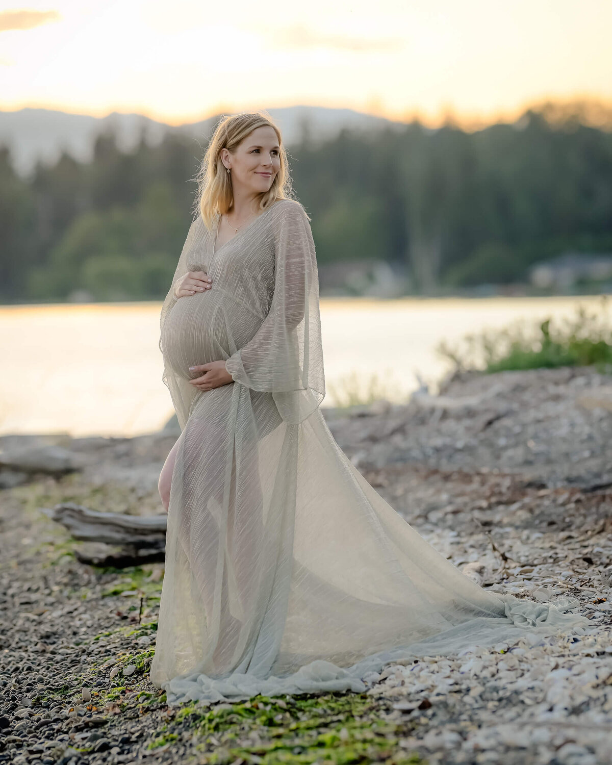 The mom-to-be shines in a sheer golden dress, beautifully framed by the serene coastal landscape. Image by Beth Benecki of E. Benecki Photography.