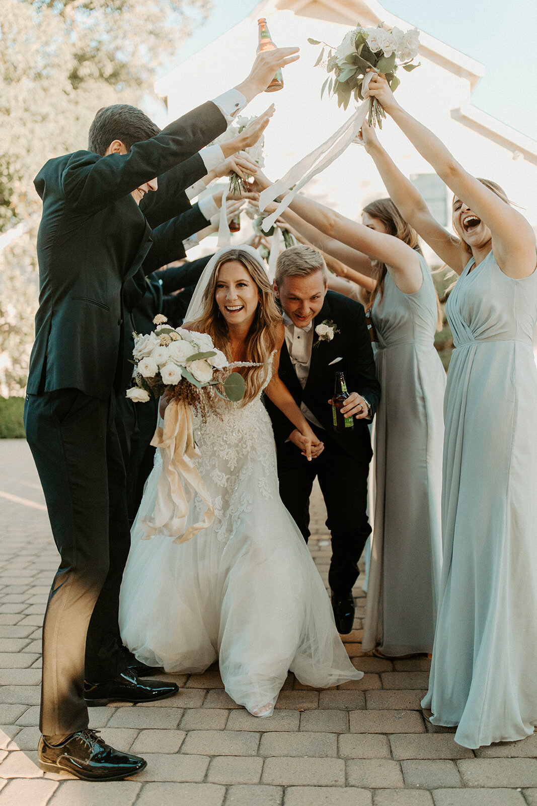 Bride and groom running under hands of bridal party