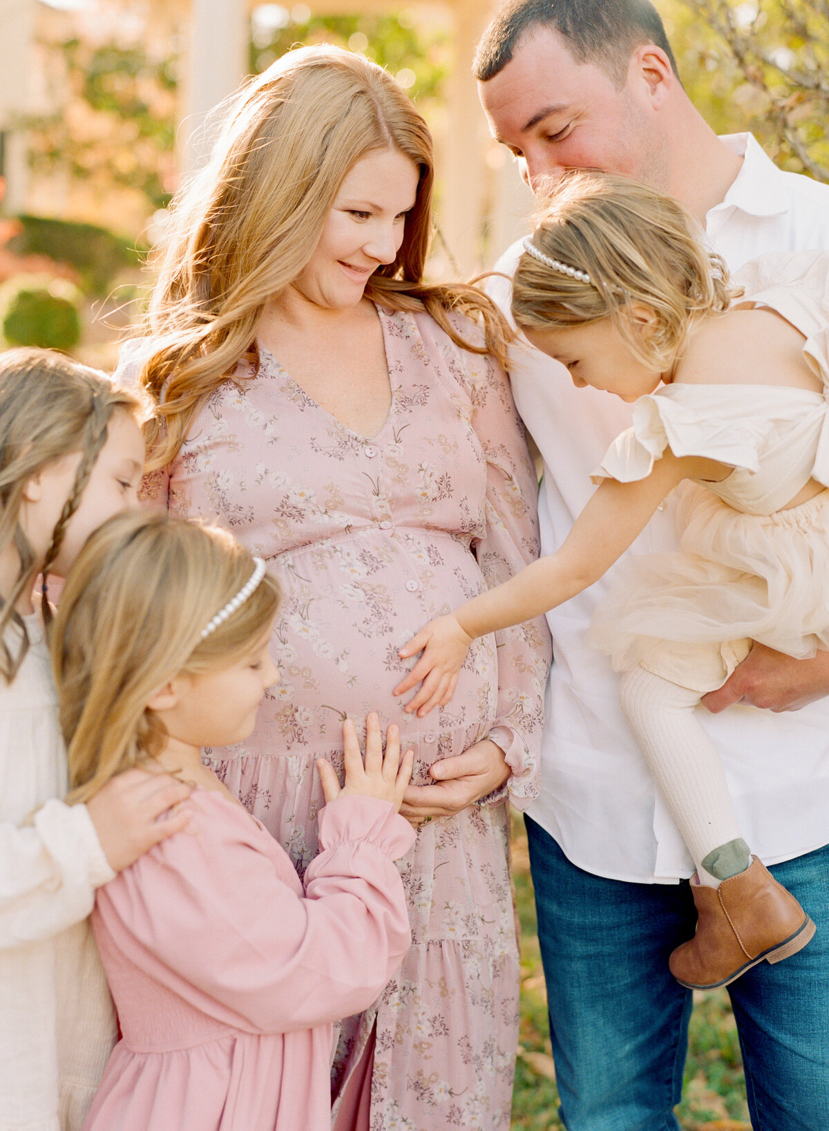 Big sisters snuggle their mom's pregnant belly during a maternity sessoin. Image by Raleigh maternity photographer A.J. Dunlap Photography.