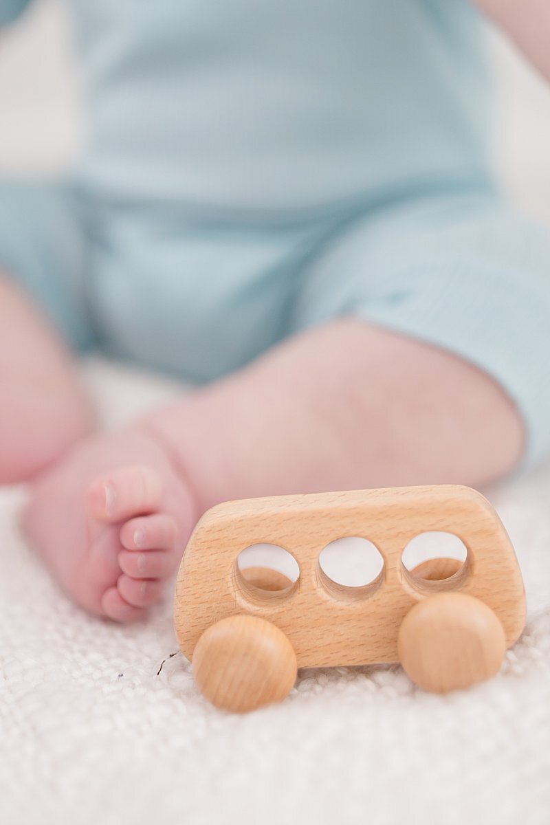 Detail photo of baby feet next to wooden car by Stamford CT Portrait studio photographer