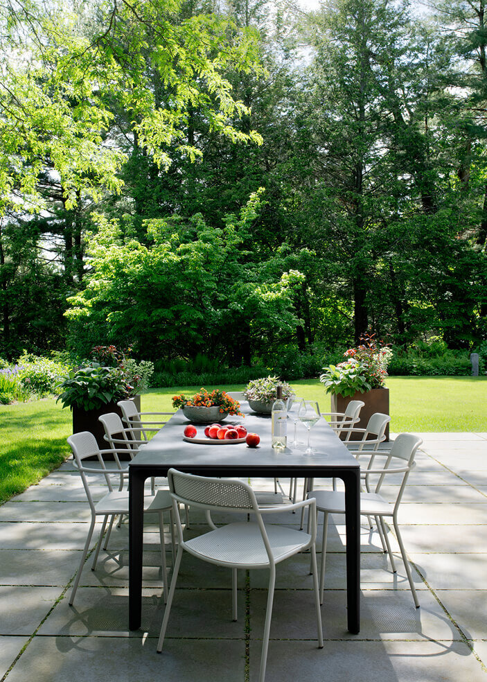 A modern outdoor dining table enhances the new patio at a Concord home, blending sleek design with the natural beauty of the outdoor space.