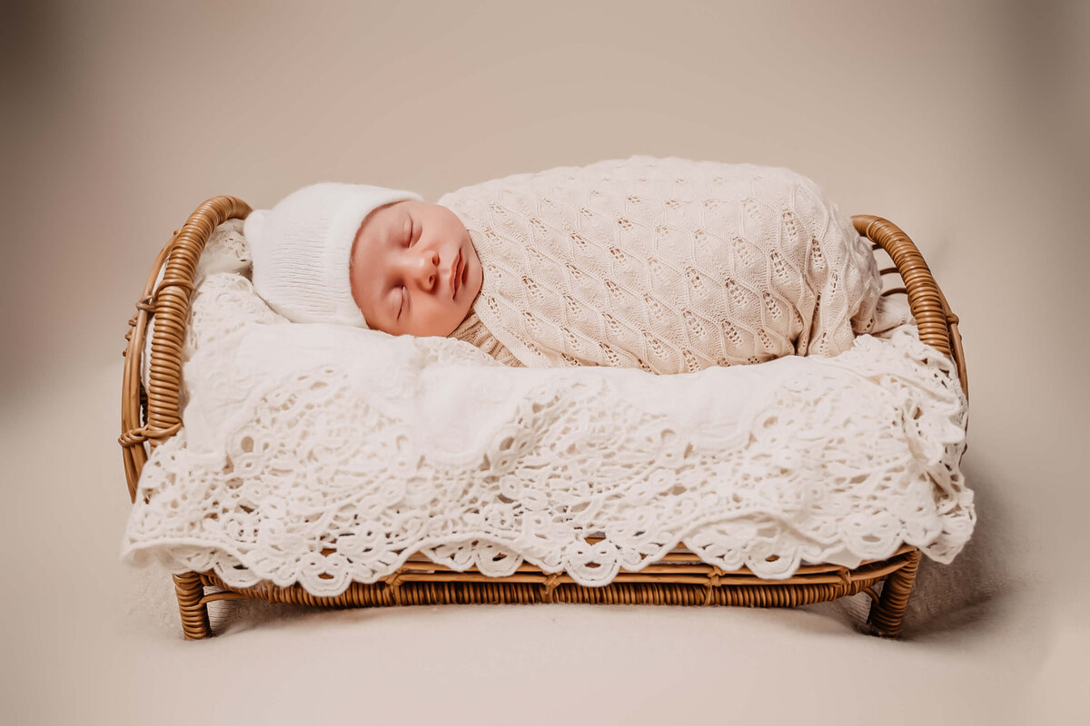 posed newborn baby wrapped and sleeping on a baby bed - Townsville Newborn Photography by Jamie Simmons