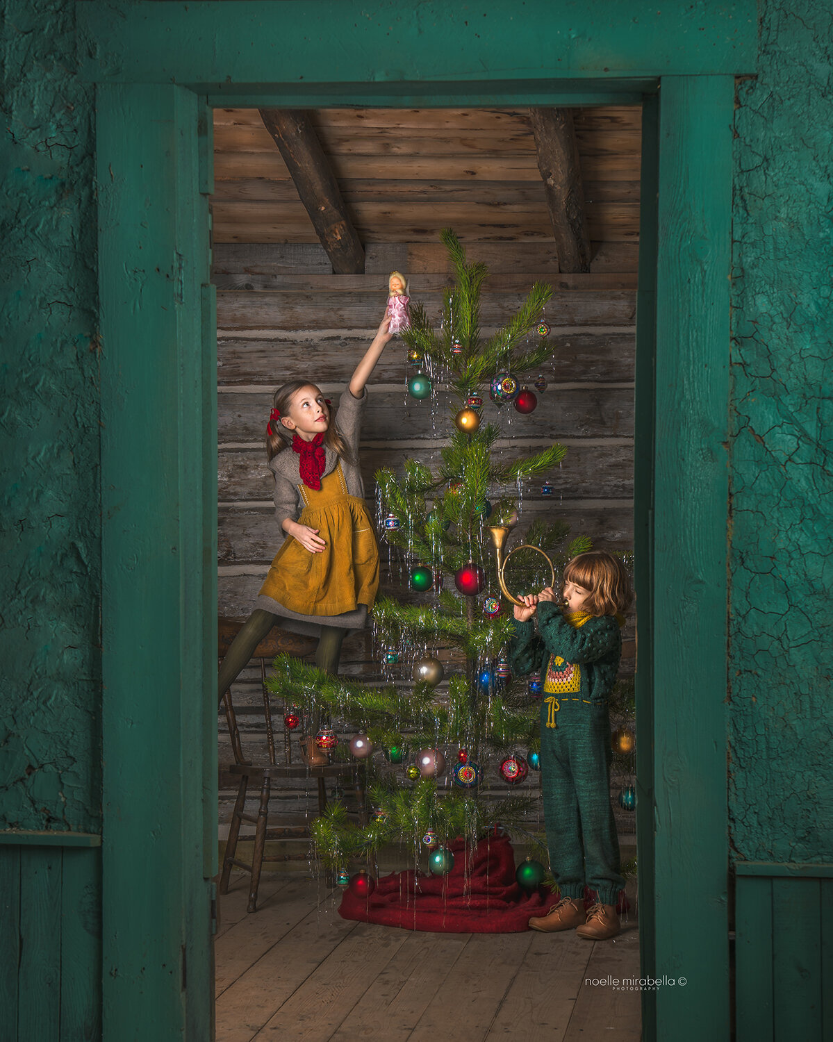 Two children in old heritage house decoration a little pine tree for Christmas and playing the trumpet.
