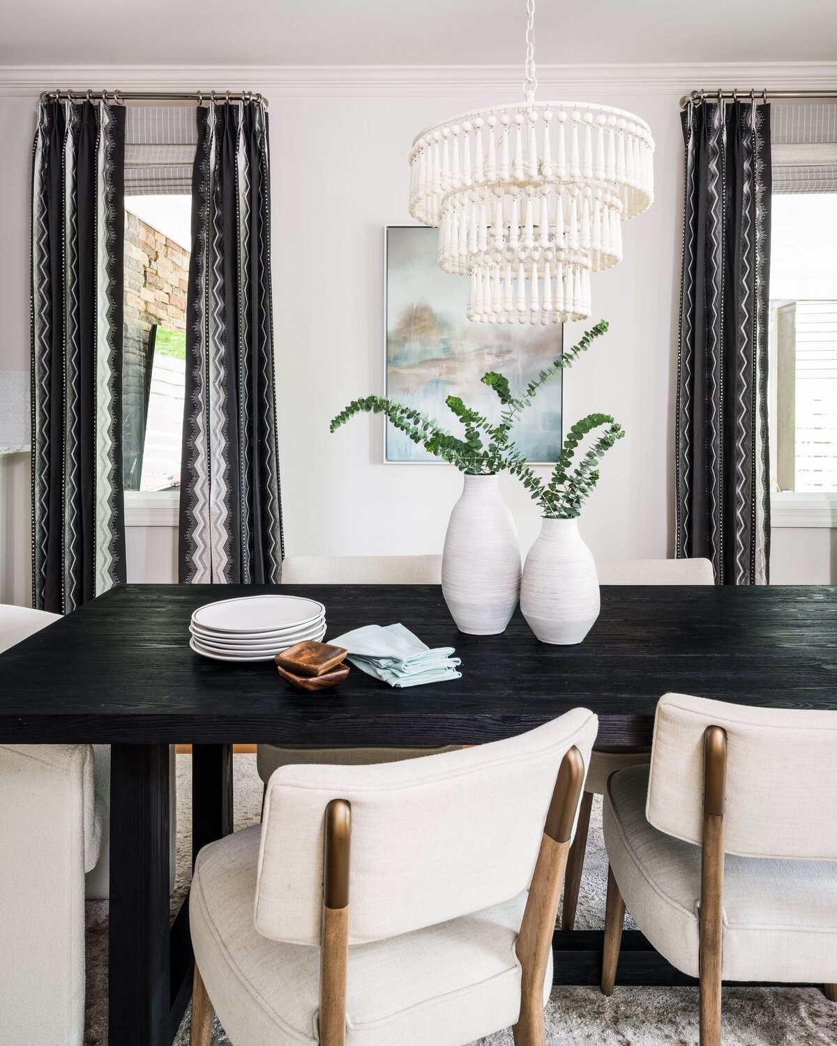 Chic dining area in Lake Norman, NC, featuring a black table, neutral decor, and modern artwork.