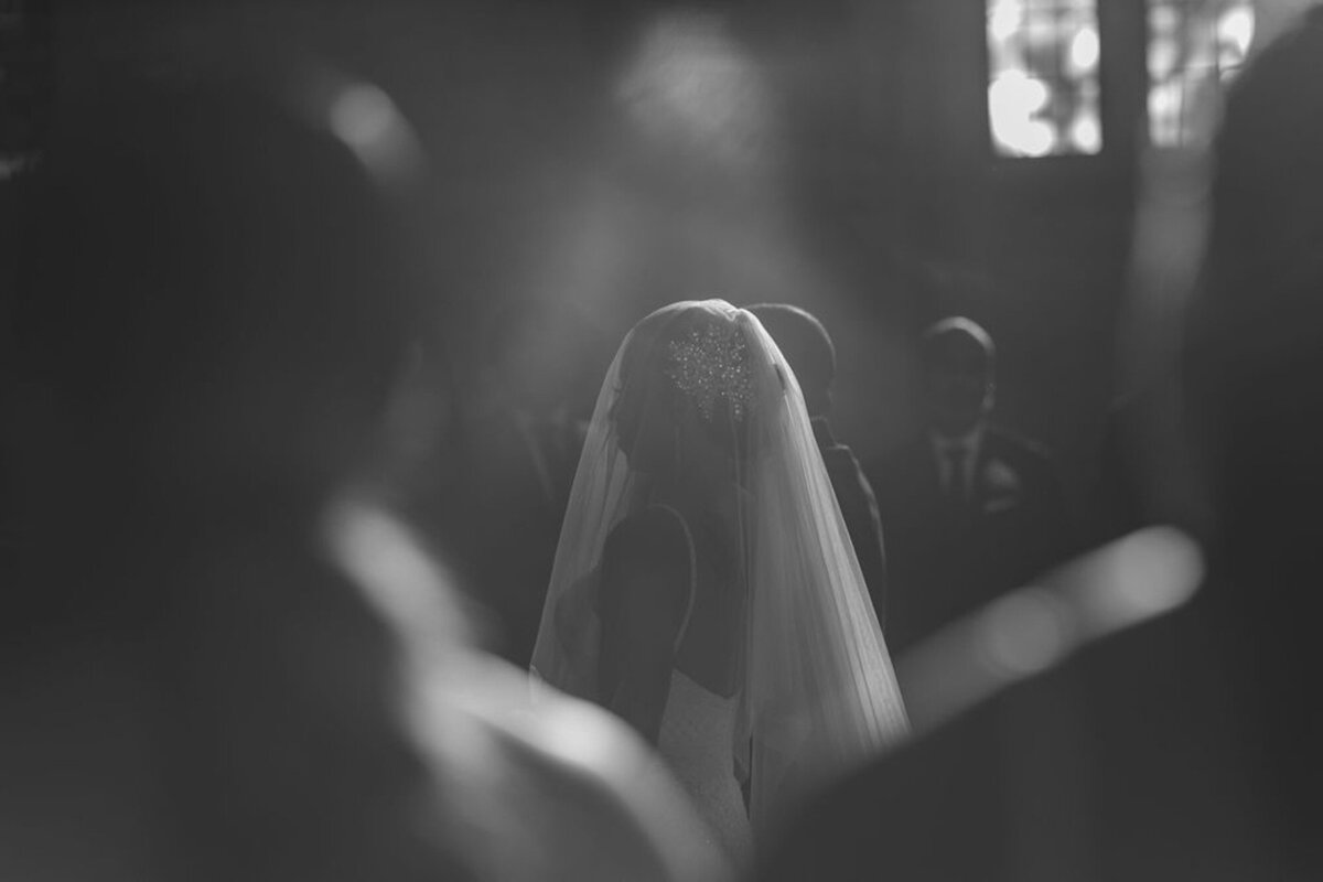 bride walking down aisle with veil over her face