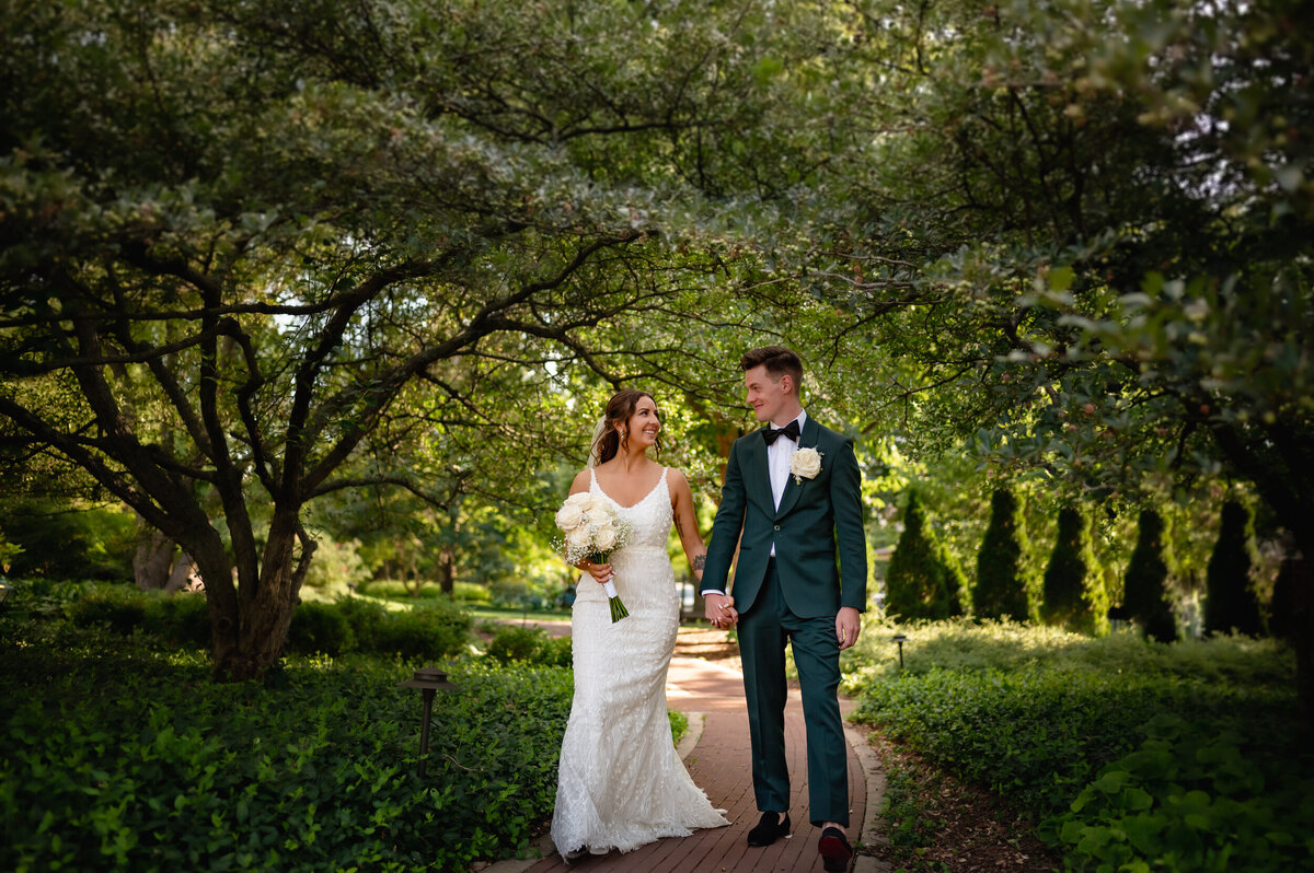 Groom wearing a green suit walks with his bride at Cheney Mansion in Oak Park, Illinois