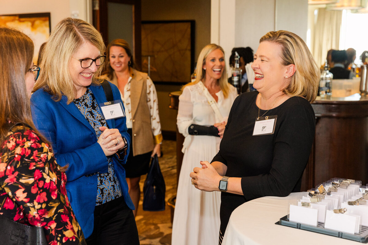 Business women talking together and laughing during evening networking event by photographer Laure Photography