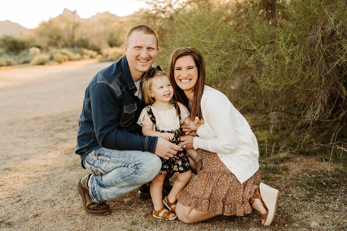 parents kneel with daughter in arizona landscape