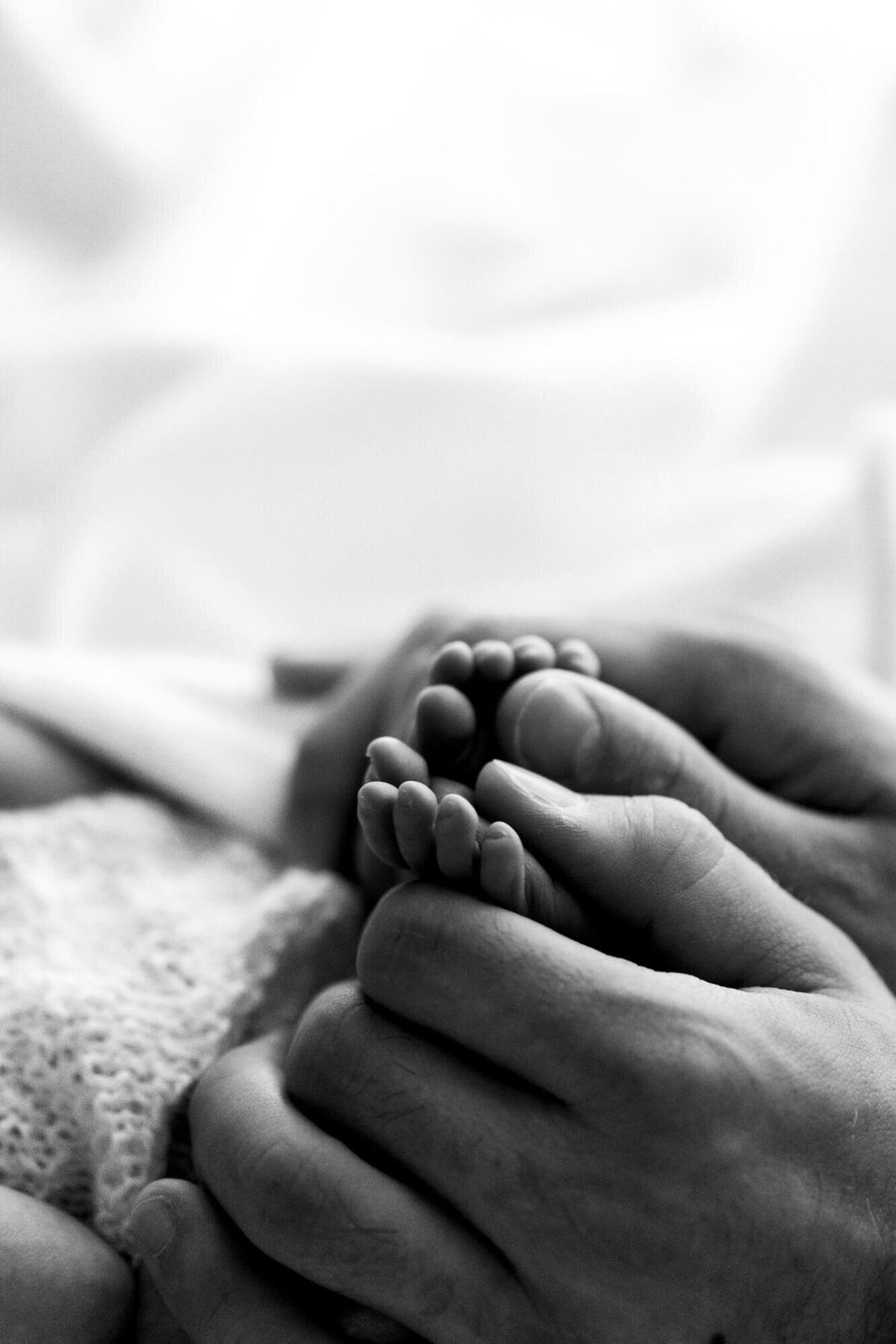 Father's hands on his newborn daughter's little feet.