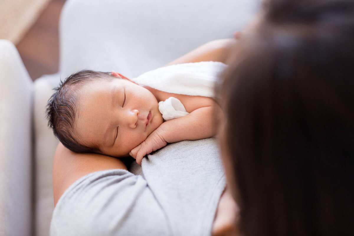 a mother holds her newborn baby while she sleeps in their encinitas home