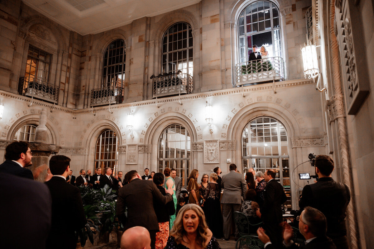 bride and groom waving from courtyard balcony on wedding day at duquesne club