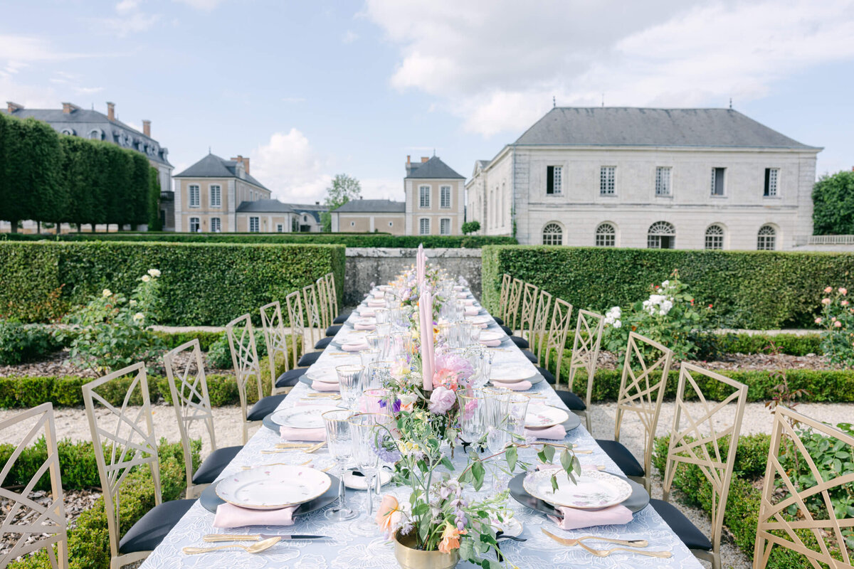 A wedding day photo of the reception table covered in blue linens, florals & candles