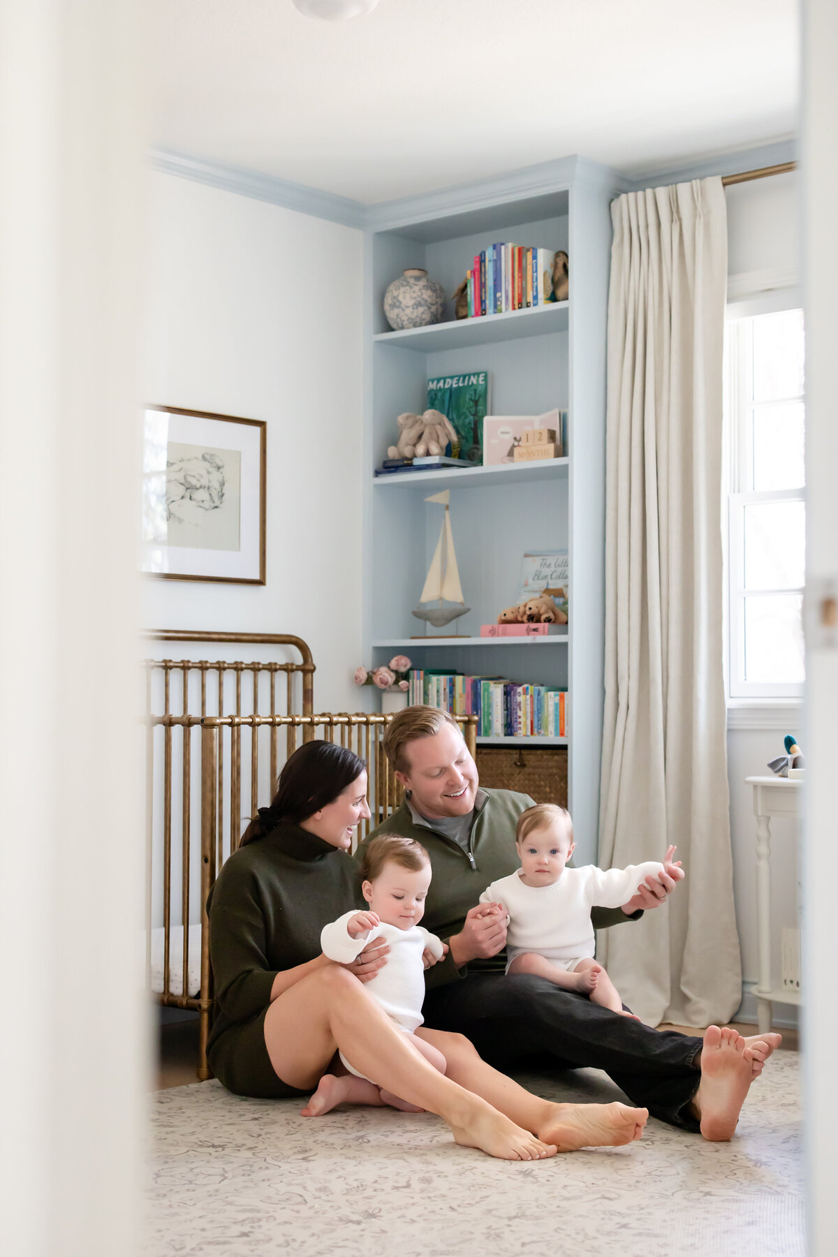a mom and dad hold thier twins in their gender-neutral classic nursery