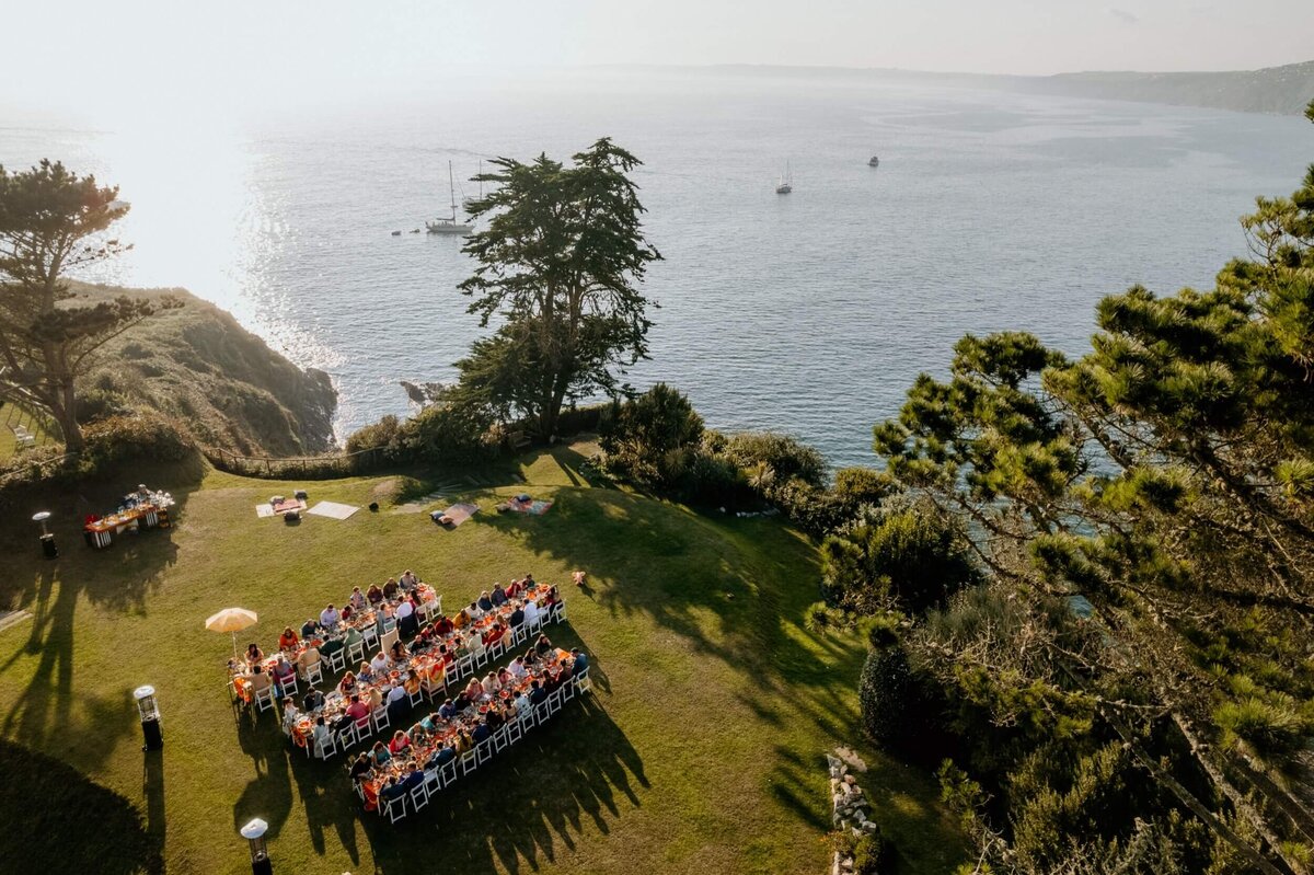 An outdoor weding breakfast setting on a lush green lawn with the sea in the background