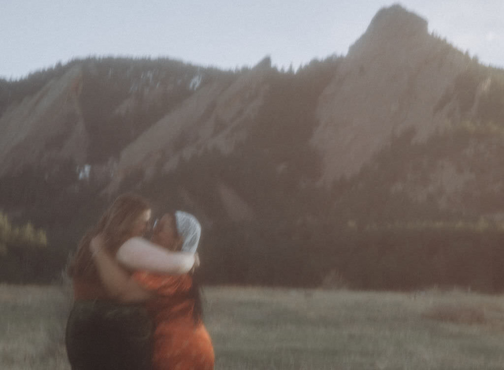 A couple kissing with the mountains behind them.