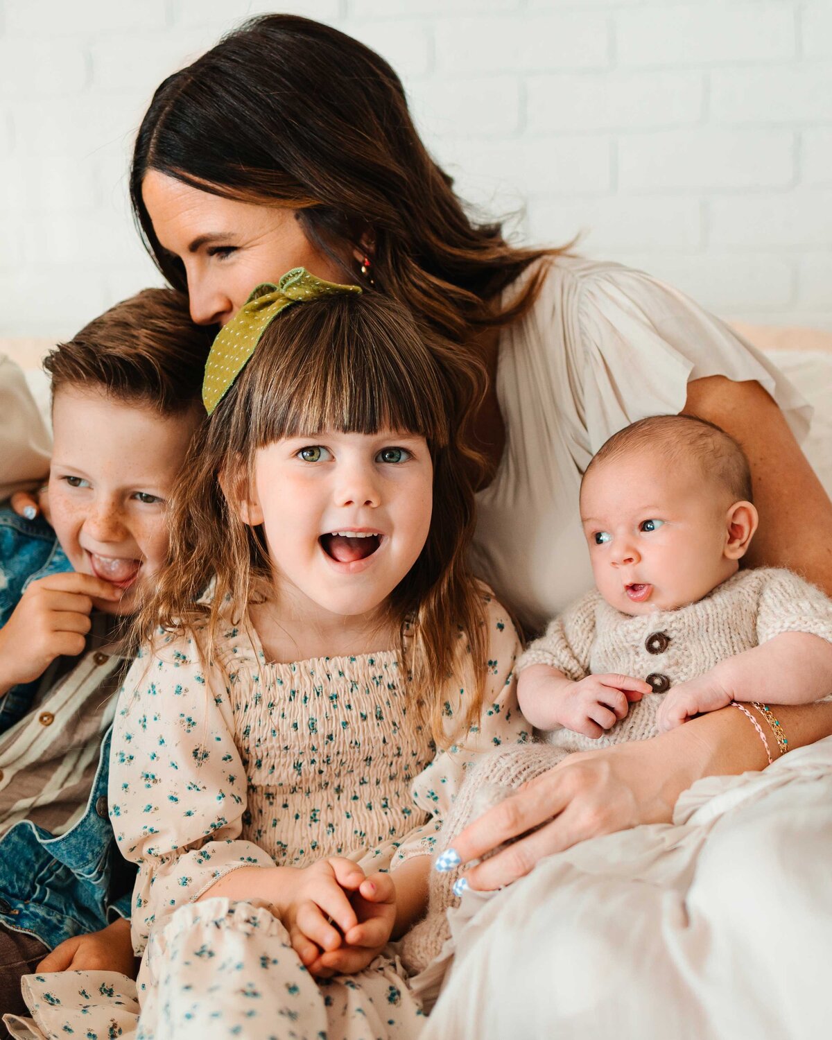A beautiful mom happily embraces her three amazing kids during a photography session in Albuquerque. The kids are smiling, and the mom's loving hug captures a joyful and heartwarming moment.