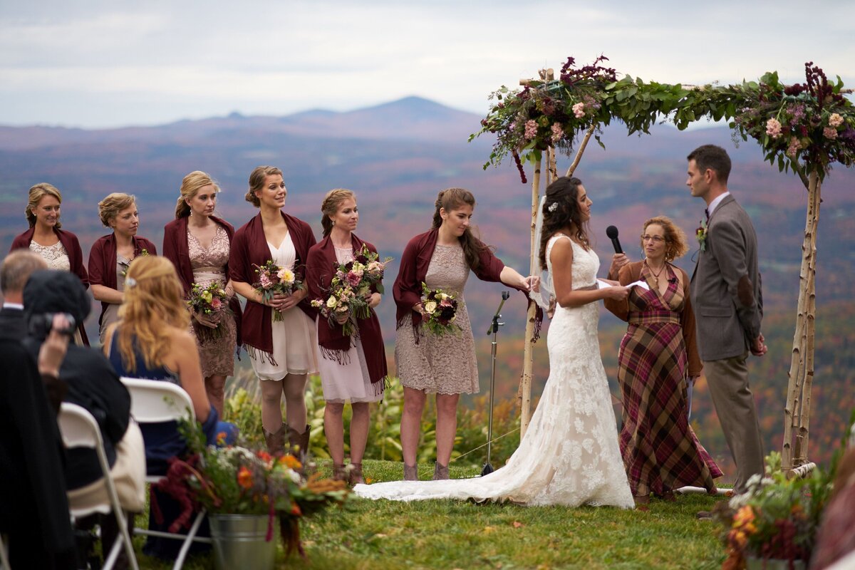 The couple exchanges heartfelt vows during their outdoor wedding ceremony, surrounded by a scenic natural backdrop. This image captures the intimate and emotional moment as they commit to each other, emphasizing the beauty of the outdoor setting and the sincerity of their promises.