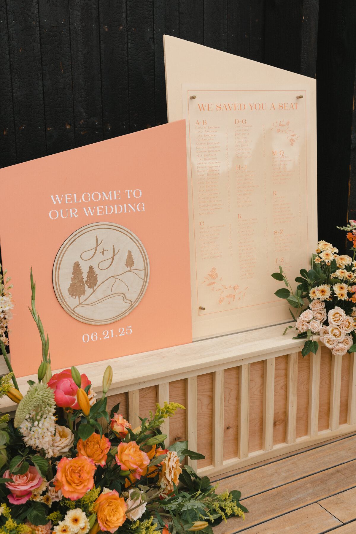 Seating chart and wedding welcome sign with coral and peach accents amongst natural wood and florals
