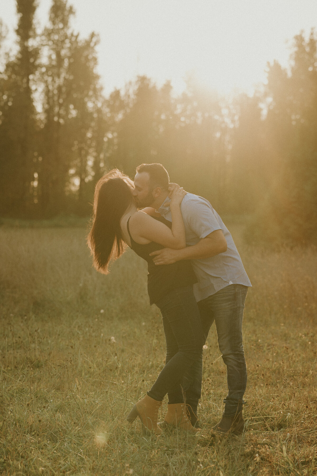 fun golden hour engagement photo of a guy kissing a girl