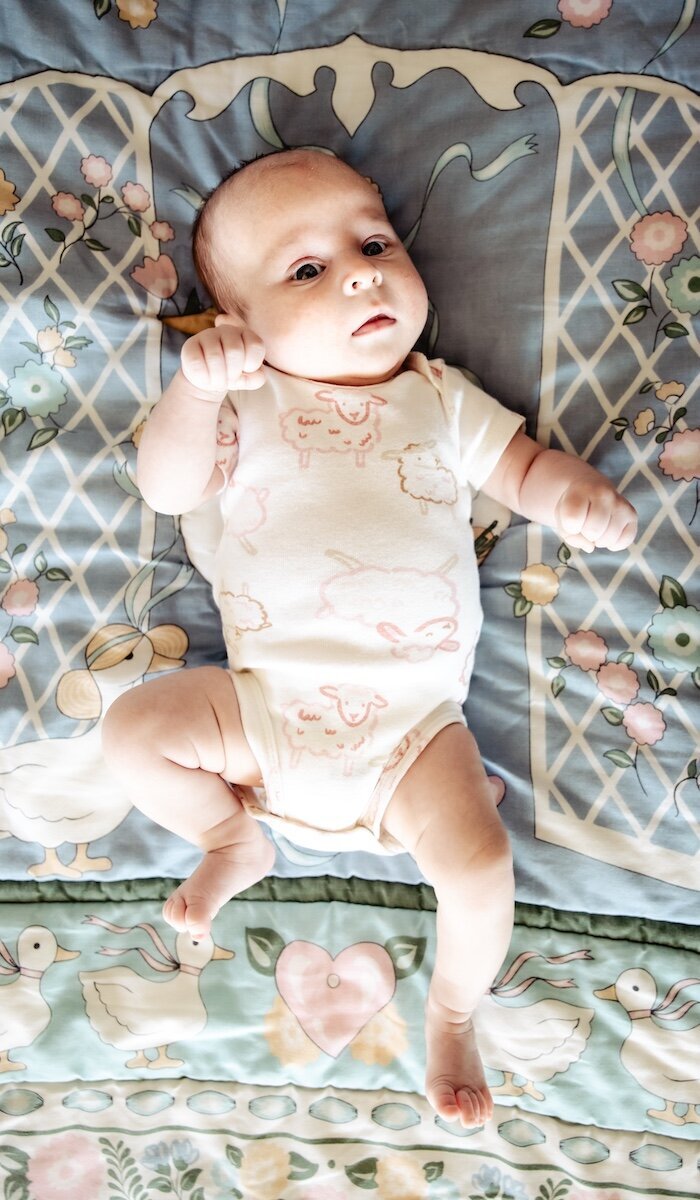 A newborn baby girl wearing a sheep onesie