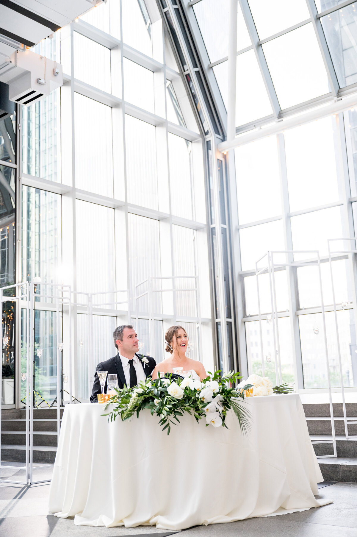 married couple smiling at their head table during their wedding reception at wintergarden ppg place