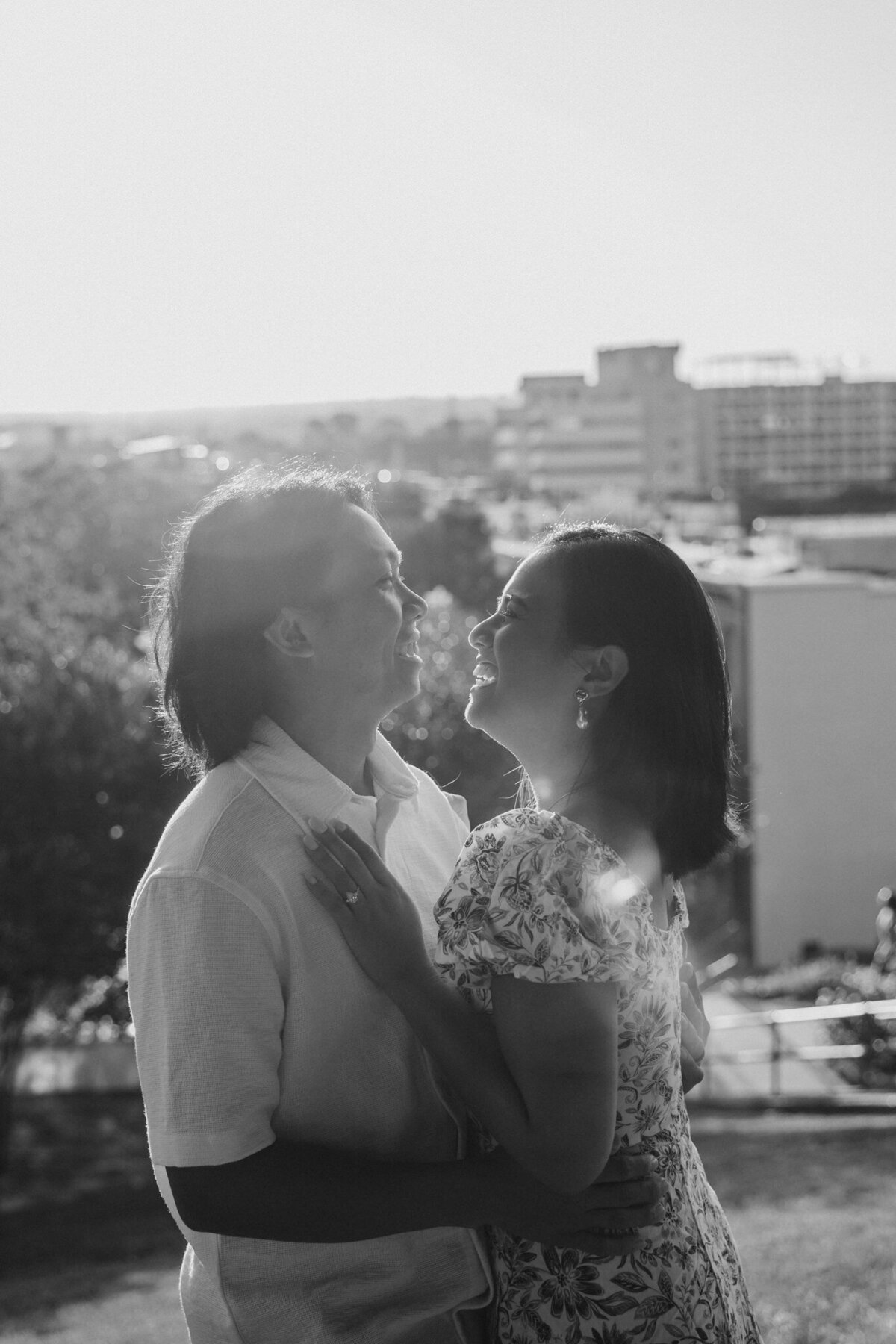 A couple laughing and standing close on a rooftop 