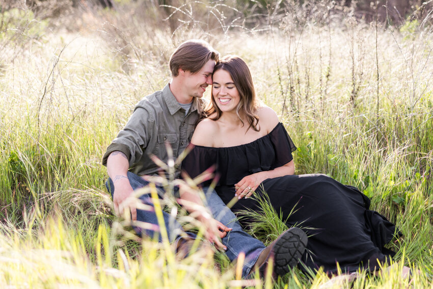 engaged-couple-sitting-and-snuggling-in-grass