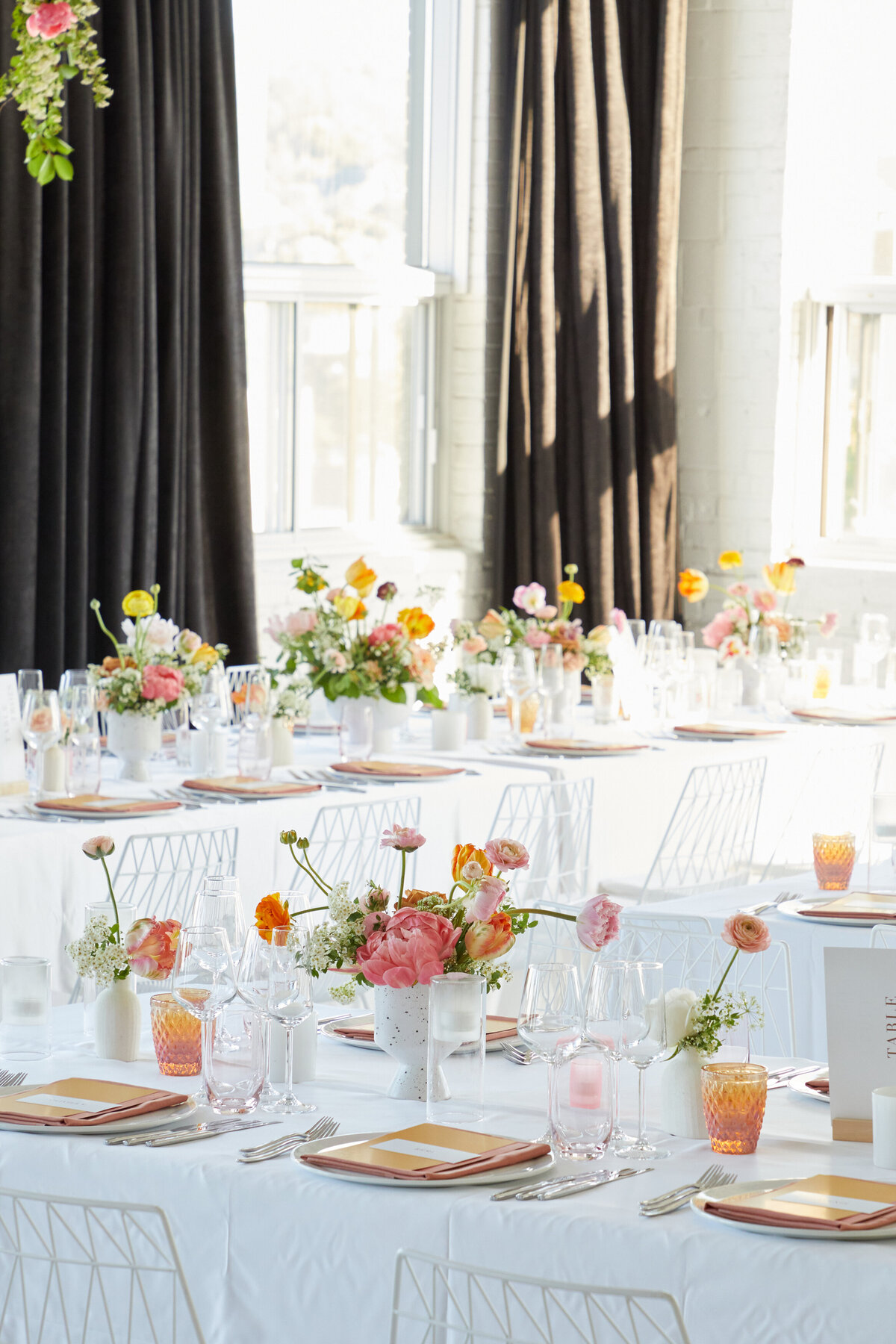 Colourful springtime floral centrepieces bathed in natural light at L’Eloi for a wedding reception.