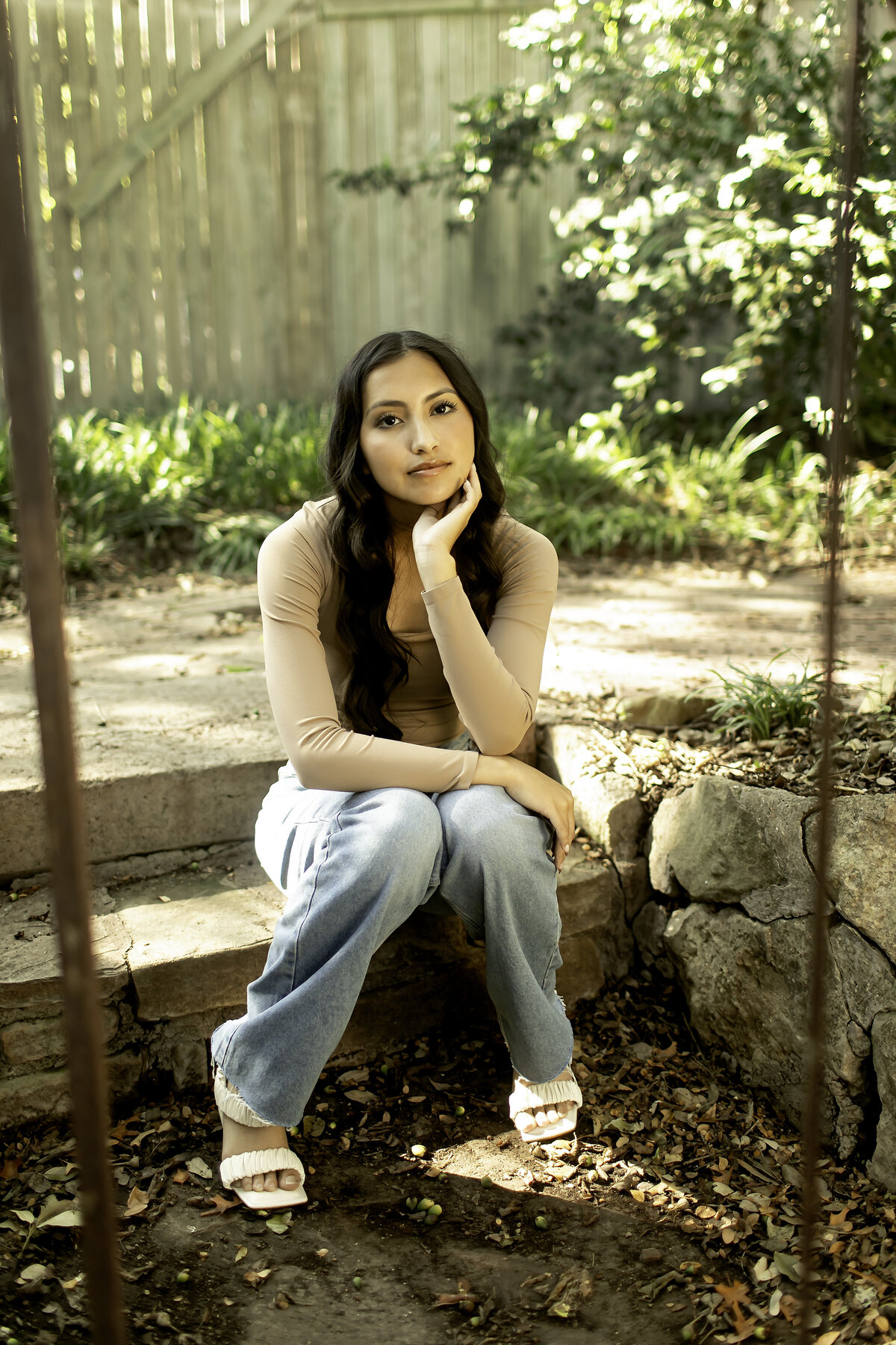 A high school senior posing gracefully by the tranquil pond at Chandor Gardens in Weatherford, capturing the beauty of nature and the excitement of graduation