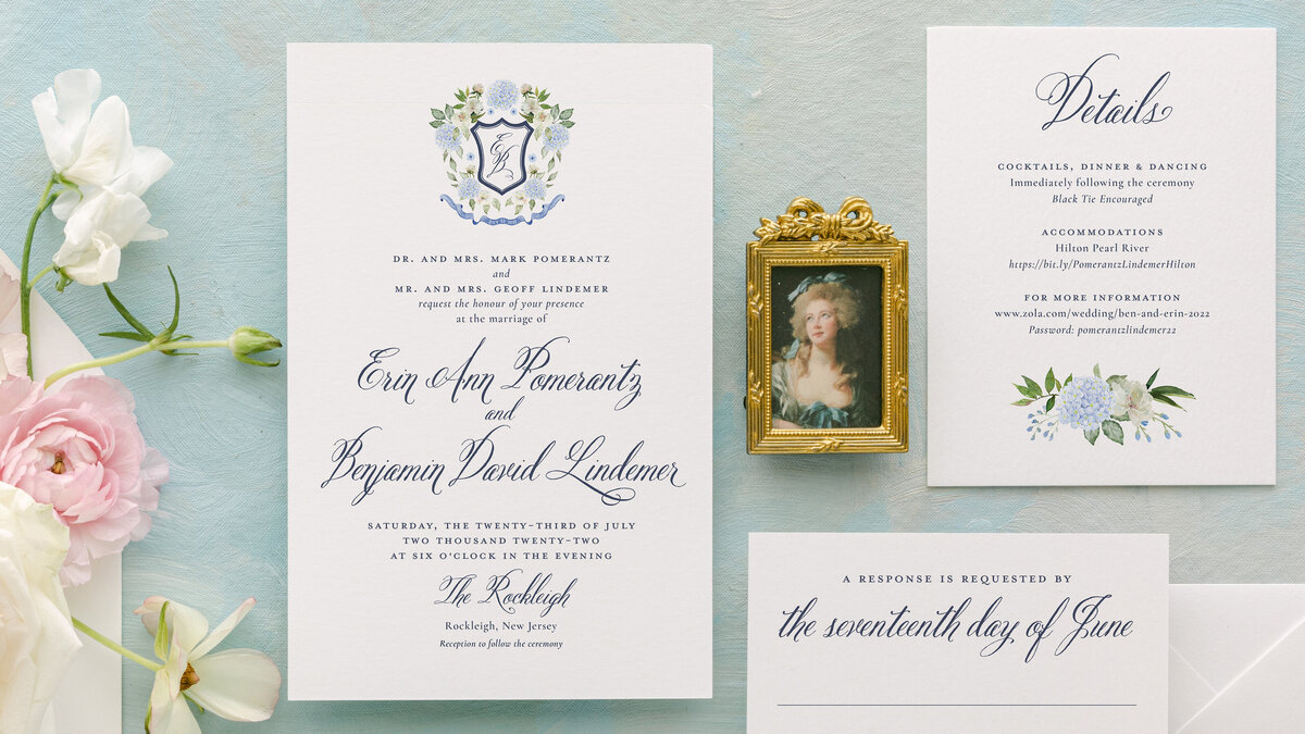 Vintage-inspired wedding invitations against a pale blue background and florals