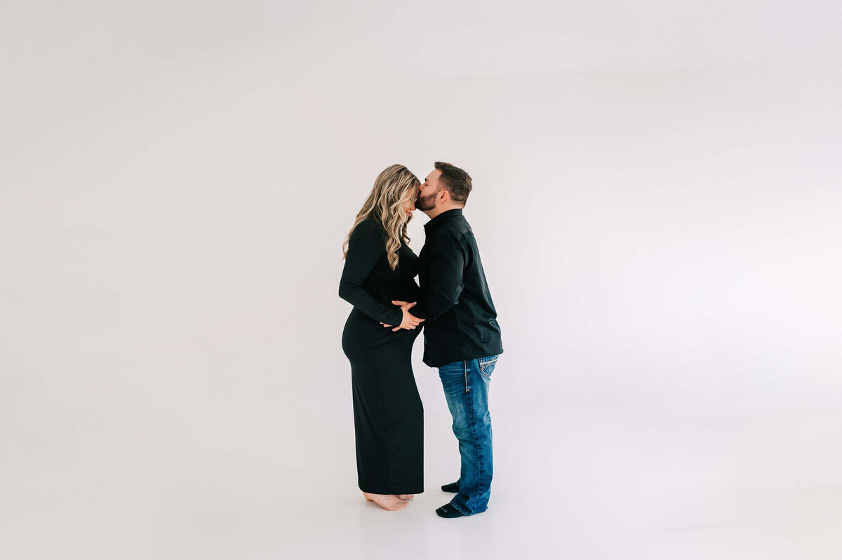 husband kissing pregnant wife forehead in Branson Mo maternity photography studio