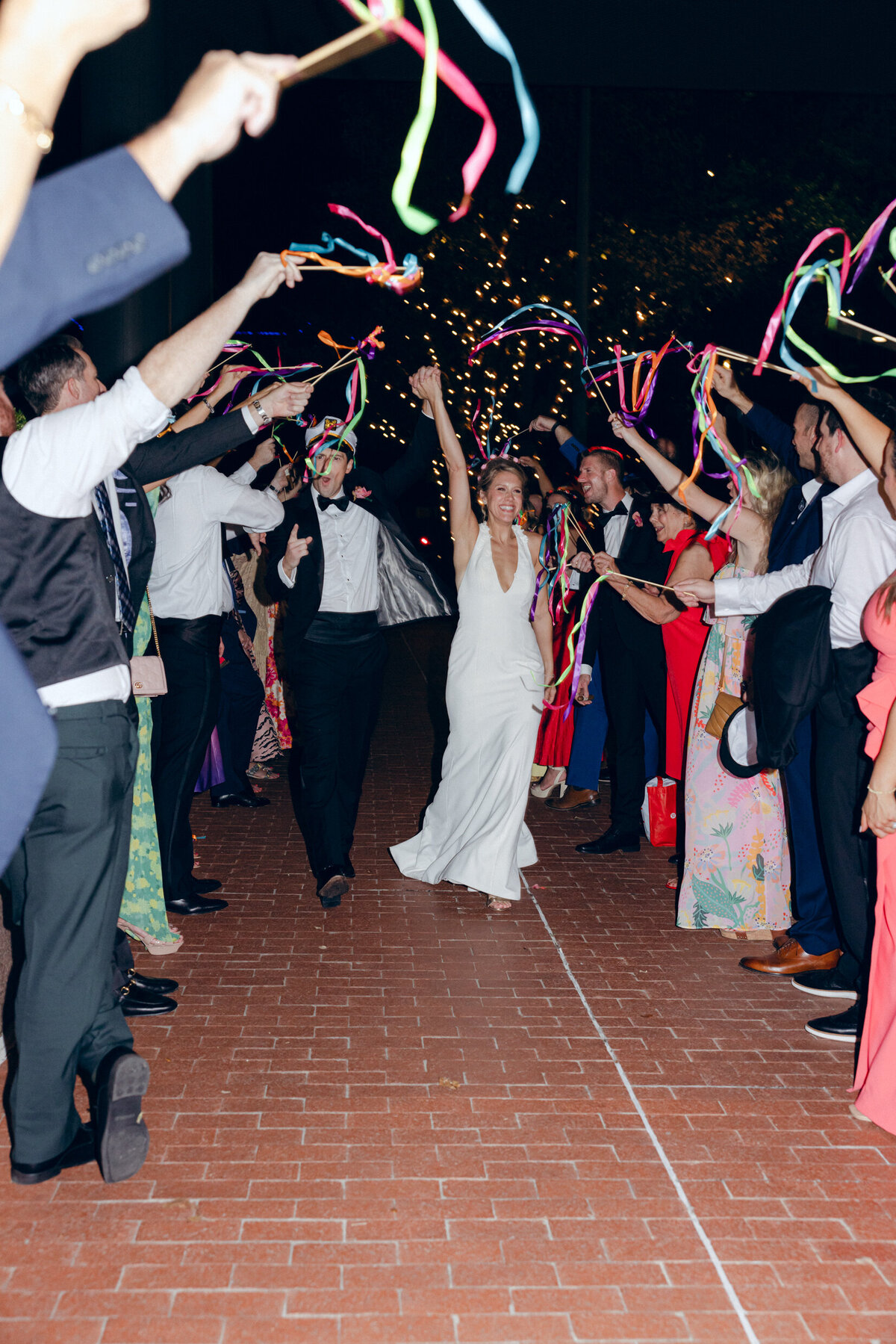 A wedding photo of the bride and groom getting to their get away car with wedding guests celebrating