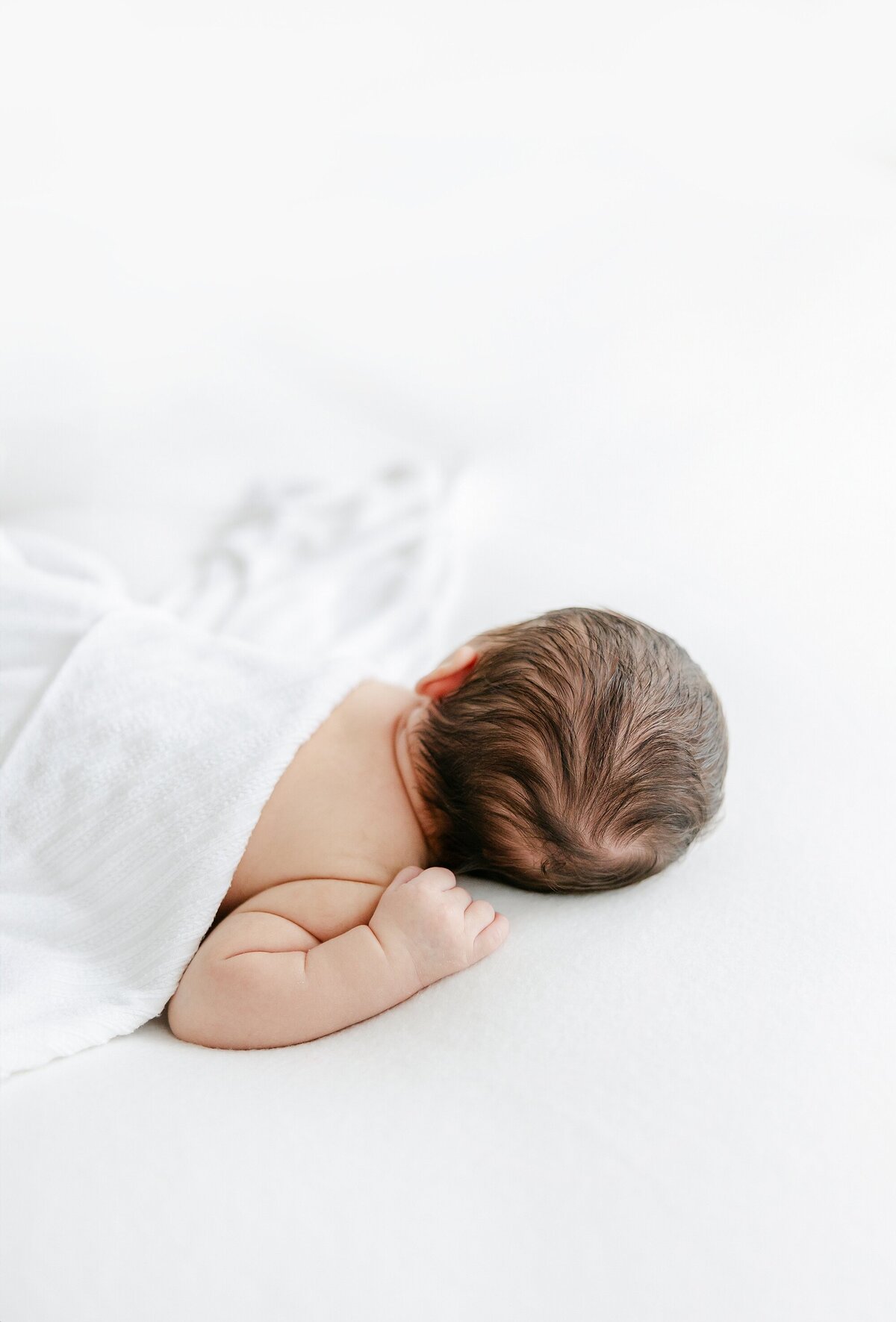 dark haired newborn laying on posing beanbag
