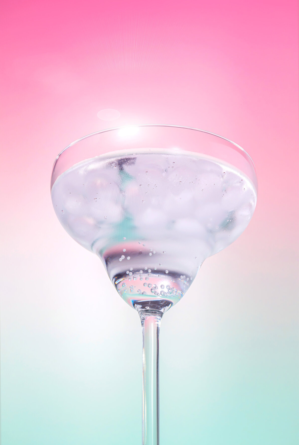 Verre transparent rempli d’eau gazeuse sur fond pastel rose et turquoise, capturé dans une lumière douce et poétique – Studio Helloday.