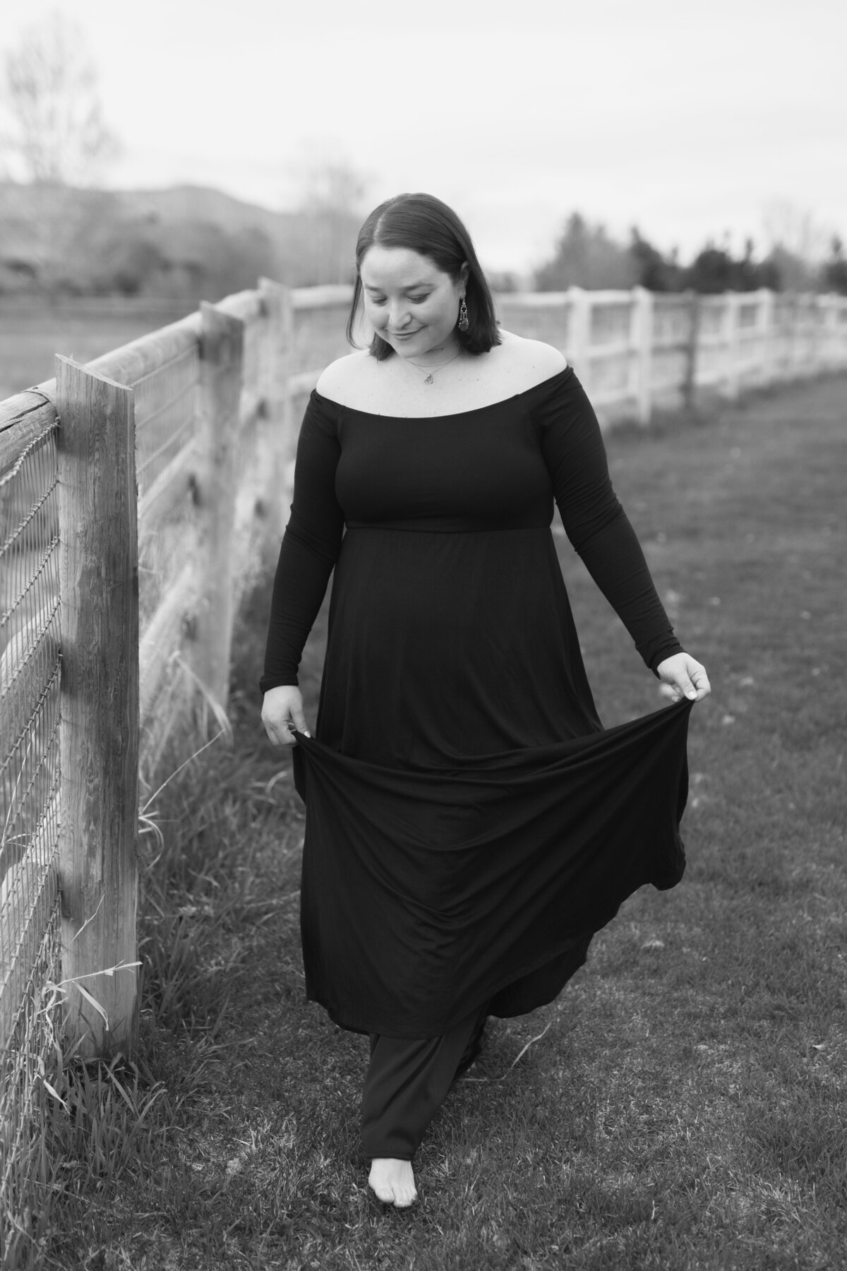 black and white image Jennifer posing by fence