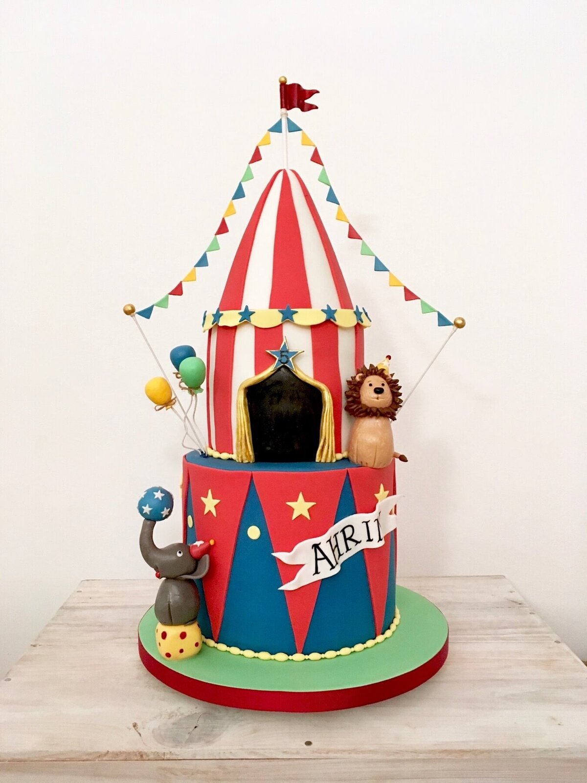 An amazing 2 tiered birthday with a circus theme including a circus tent, elephant, lion and balloons