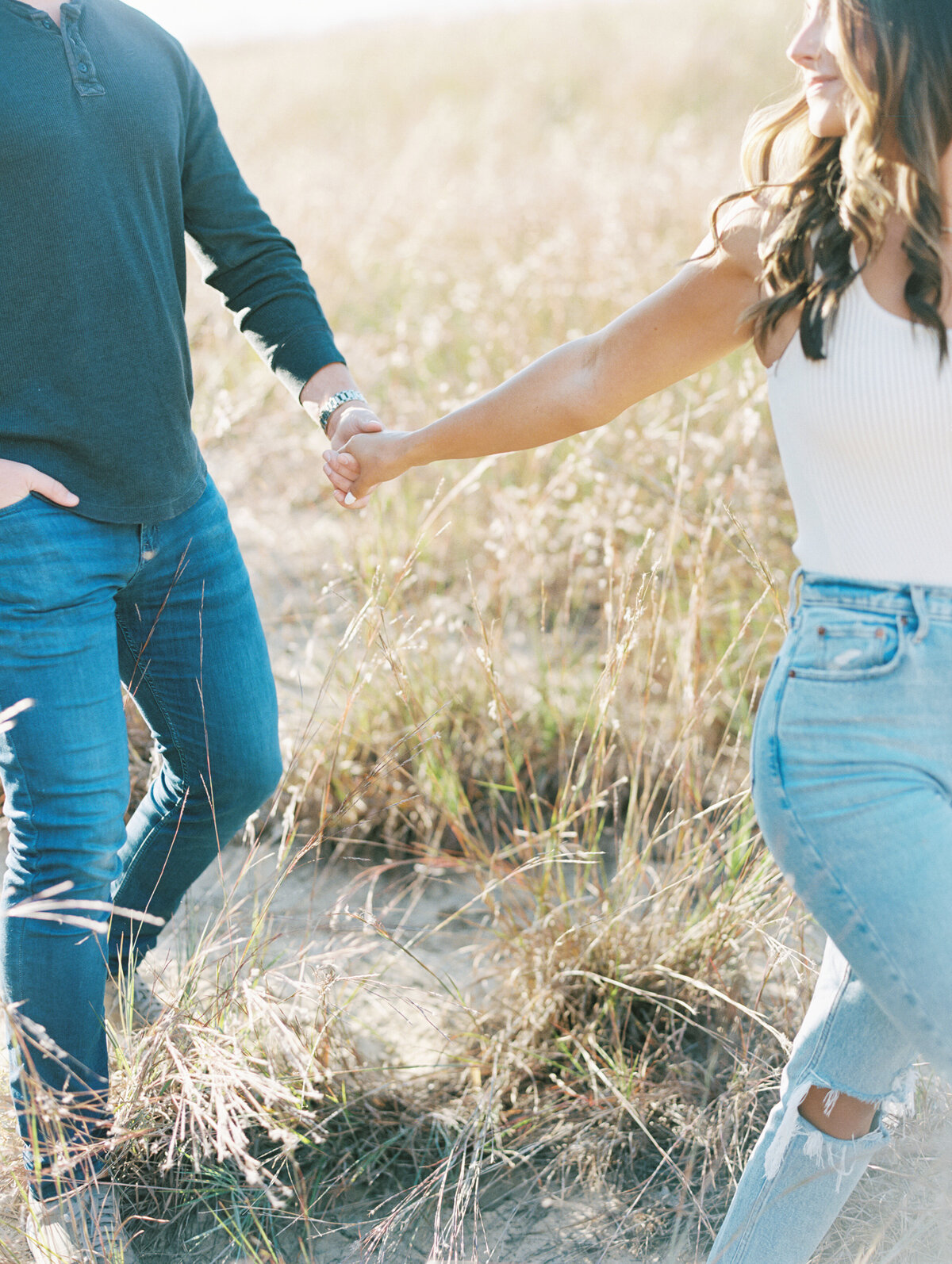 Bride and groom holding hands walking through field photographed by Chicago editorial wedding photographer Arielle Peters