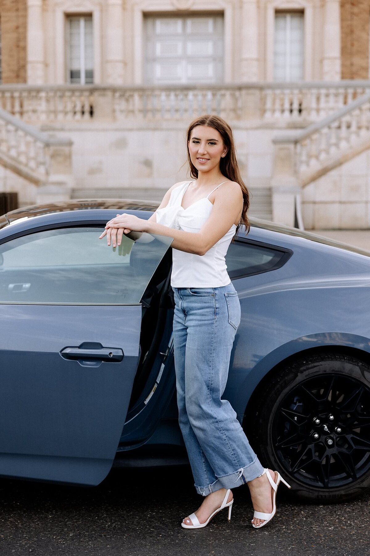 Senior standing next to her car door, smiling at the camera.