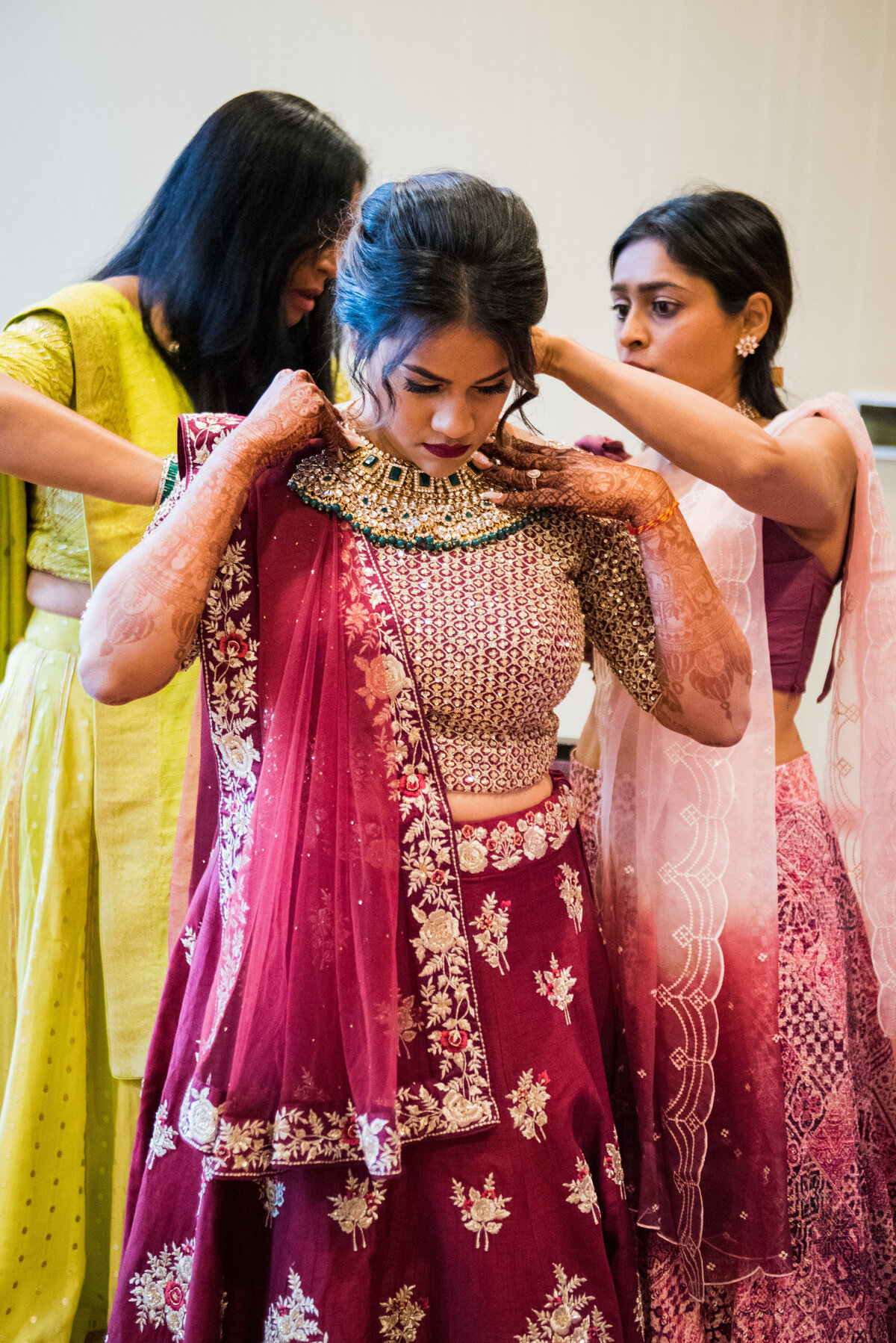 An Indian bride gets help from her bridesmaids as they put on the traditional ceremonial outfit.
