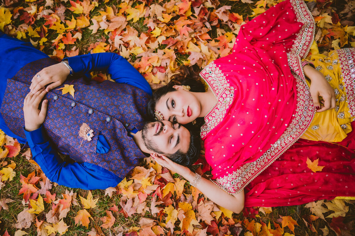 an engaged couple laying down head to head on fall leaves at sayen gardens nj
