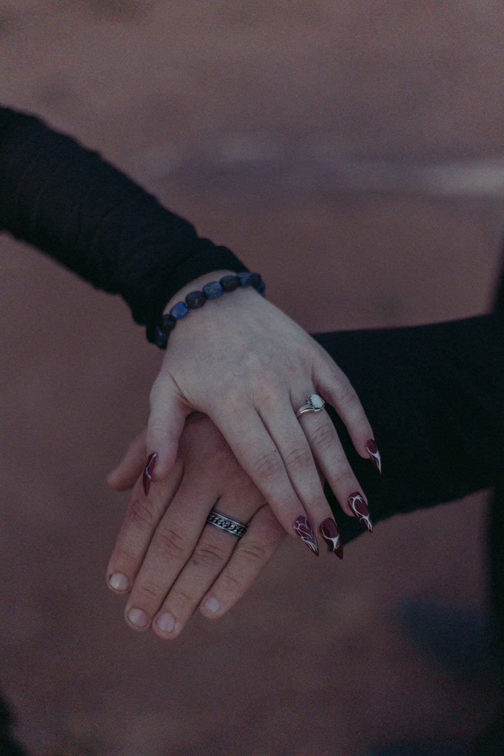 Two hands laid on top of each other showing off wedding rings.