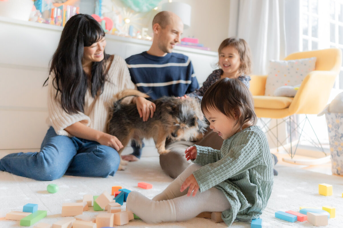 Family of four with dog in child's bedroom toddler with blocks